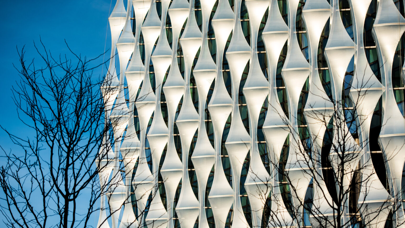 Sunlit exterior panels of the U.S. Embassy in London against a blue sky.