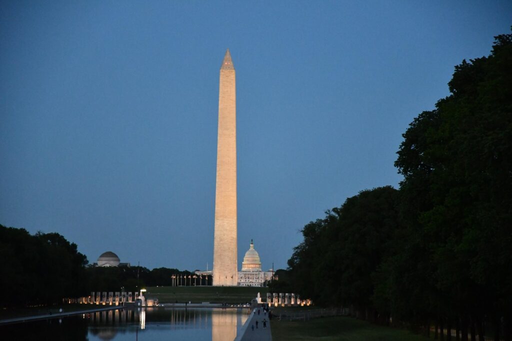 Washington Monument and U.S. Capitol seen beyond the Lincoln Memorial Reflecting Pool at dusk.