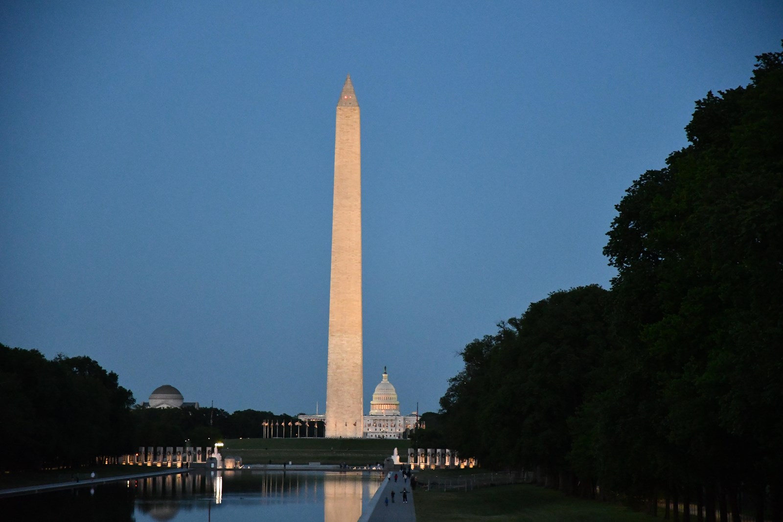 Washington Monument and U.S. Capitol seen beyond the Lincoln Memorial Reflecting Pool at dusk.